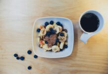 건강에 영향을 미치는 음식의 질 sliced bananas with berries and peanut butter beside cup of coffee on table