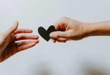 개인의 삶의 질을 결정 짓는 정신적 웰빙 person reaching black heart cutout paper