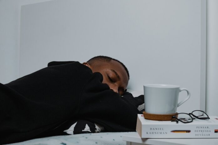 Photo by Nubelson Fernandes a man sleeping on a bed next to a stack of books