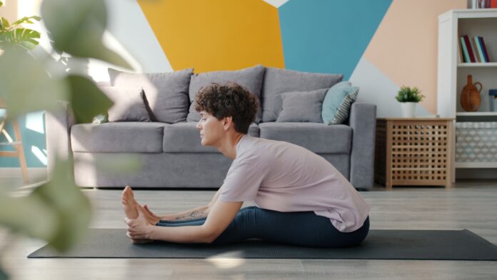 Photo by Vitaly Gariev Woman stretching on yoga mat in living room.