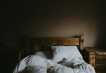 “현대인의 수면, 트렌드와 함께 달라진 슬립 루틴의 변화” white bed comforter set and brown wooden bed frame beside brown wooden nightstand