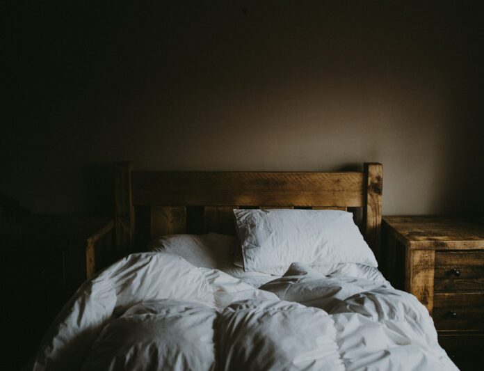 Photo by Annie Spratt white bed comforter set and brown wooden bed frame beside brown wooden nightstand