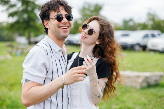 Young couple laughing outdoors on a sunny day.